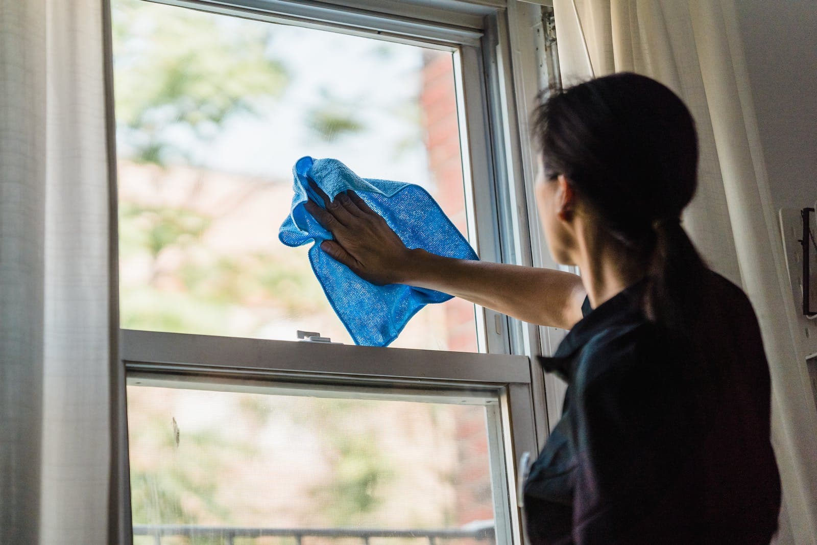 Vrouw in zwart shirt die de ramen afneemt