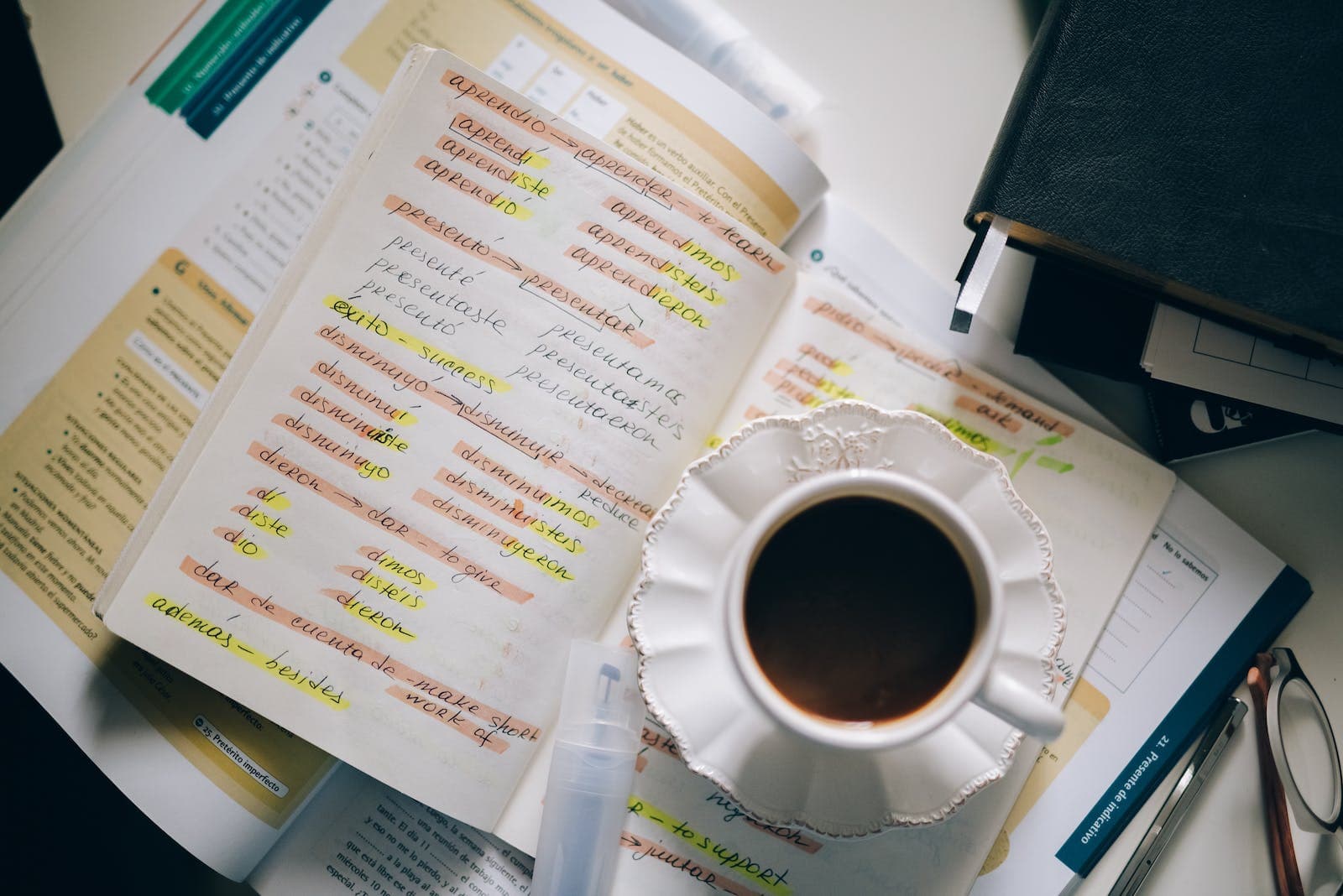 een kop koffie bovenop aantekeningen van iemand die een nieuwe taal leert