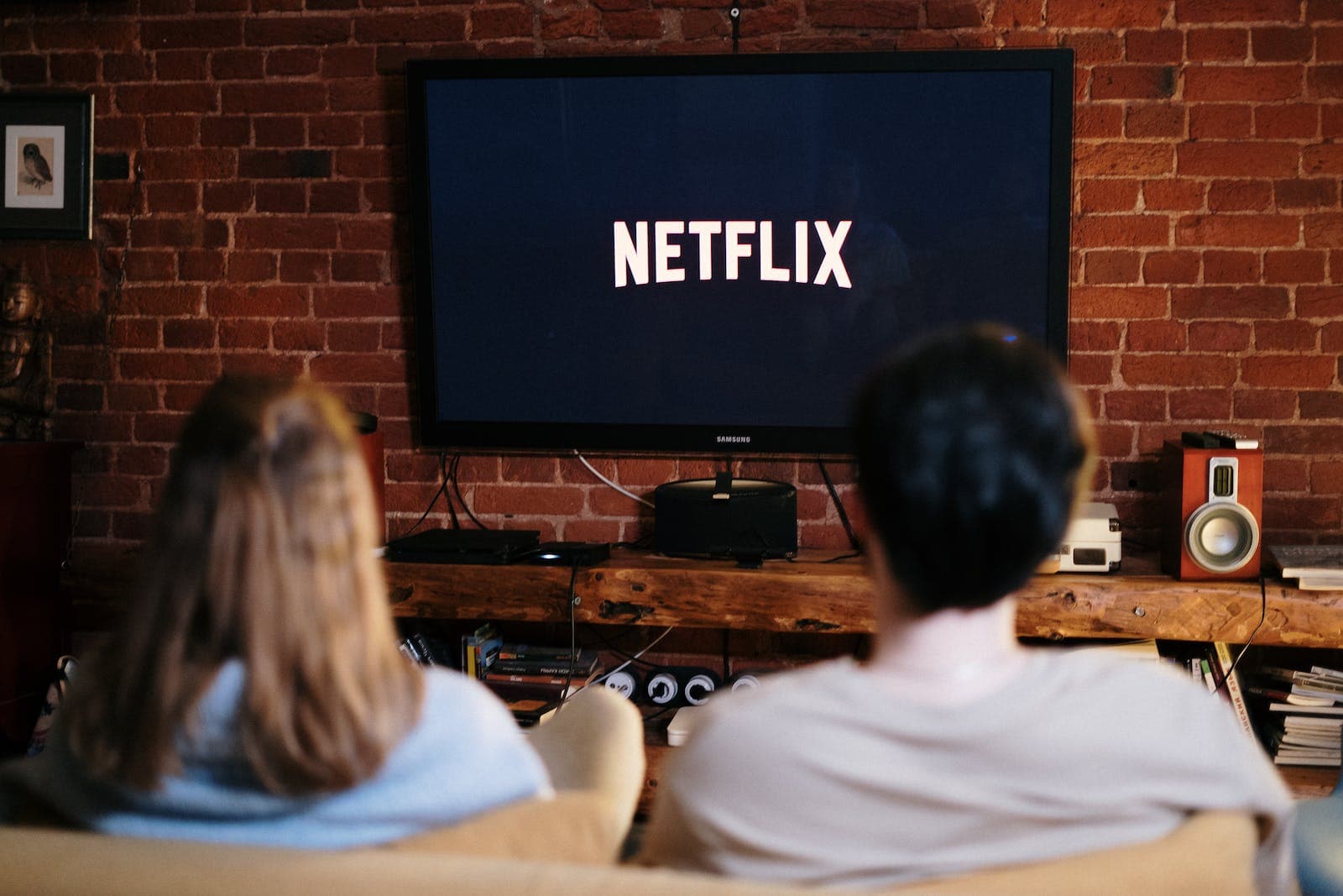 man en vrouw zitten op de bank voor een grote tv met netflix