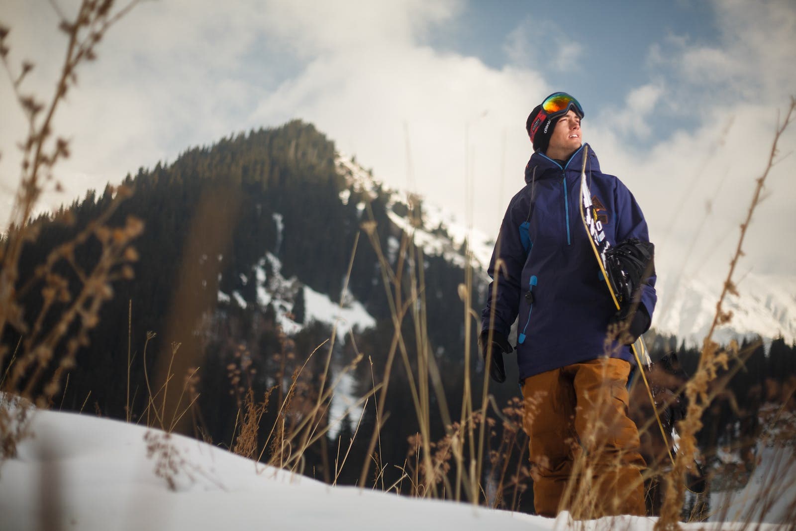 Man met snowboard die in het sneeuwachtig gebied loopt