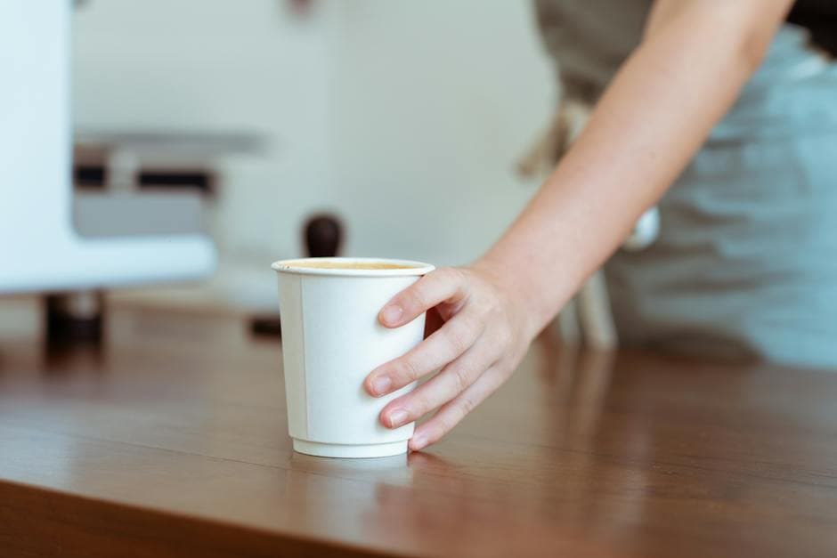 Barista die koffie serveert in papieren beker