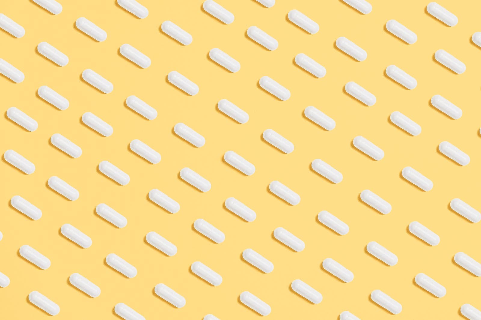 witte pillen tegen een gele achtergrond