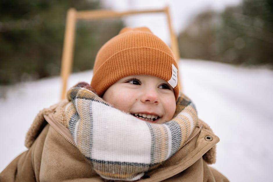 Portret van een blije jongen in de winter, gekleed in een warme jas en een muts, met een sneeuwbedekt landschap op de achtergrond.