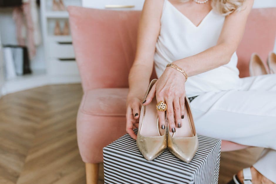 Vrouw in een witte, mouwloze jurk die gouden leren, open tenen hakken draagt.