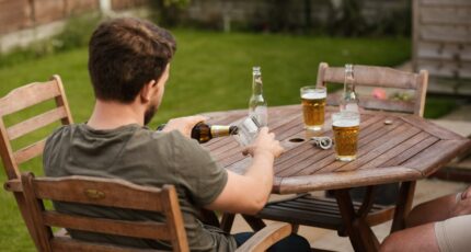 Man die een biertje inschenkt in zijn tuin