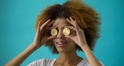 Vrouw houdt twee bitcoins voor haar ogen