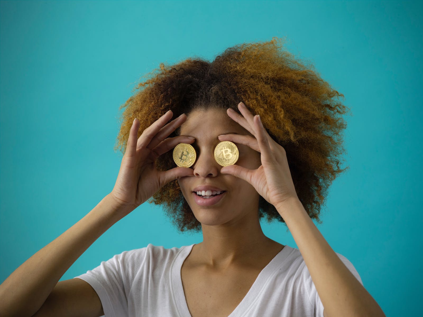 Vrouw houdt twee bitcoins voor haar ogen