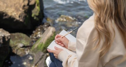 Vrouw die aan het schrijven is bij een beekje