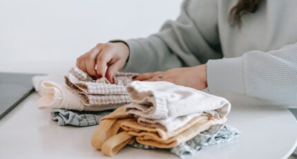 Unrecognizable woman arranging baby clothes at table