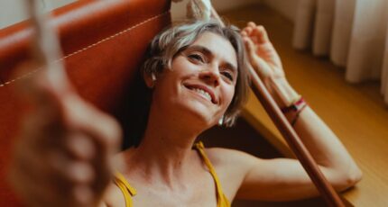 Een oudere vrouw die in hangmat relaxt luisterend naar selfcare poecast