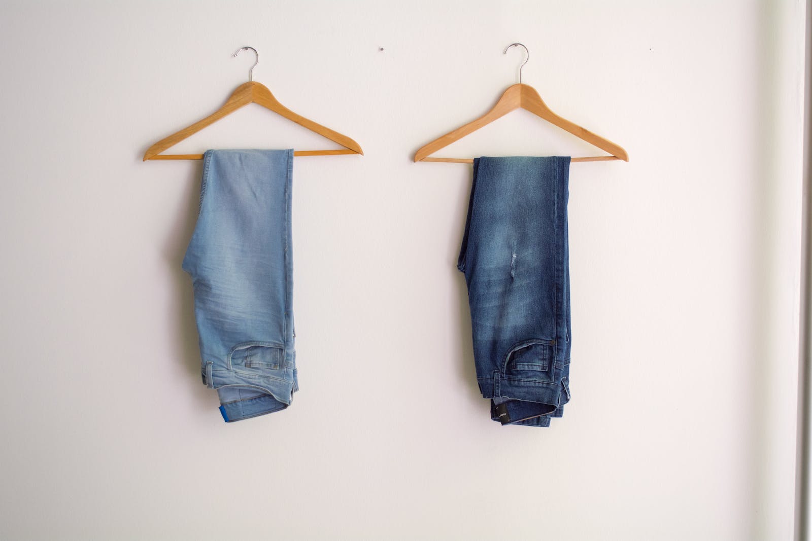 twee jeans aan een kleerhanger, lichtblauw en donkerblauw