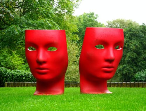 Red Human Face Monument on Green Grass Field