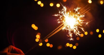 Iemand houdt een brandend sterretje (vorm van vuurwerk) vast