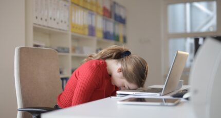 een vrouw die vermoeid is en met hoofd op laptop valt