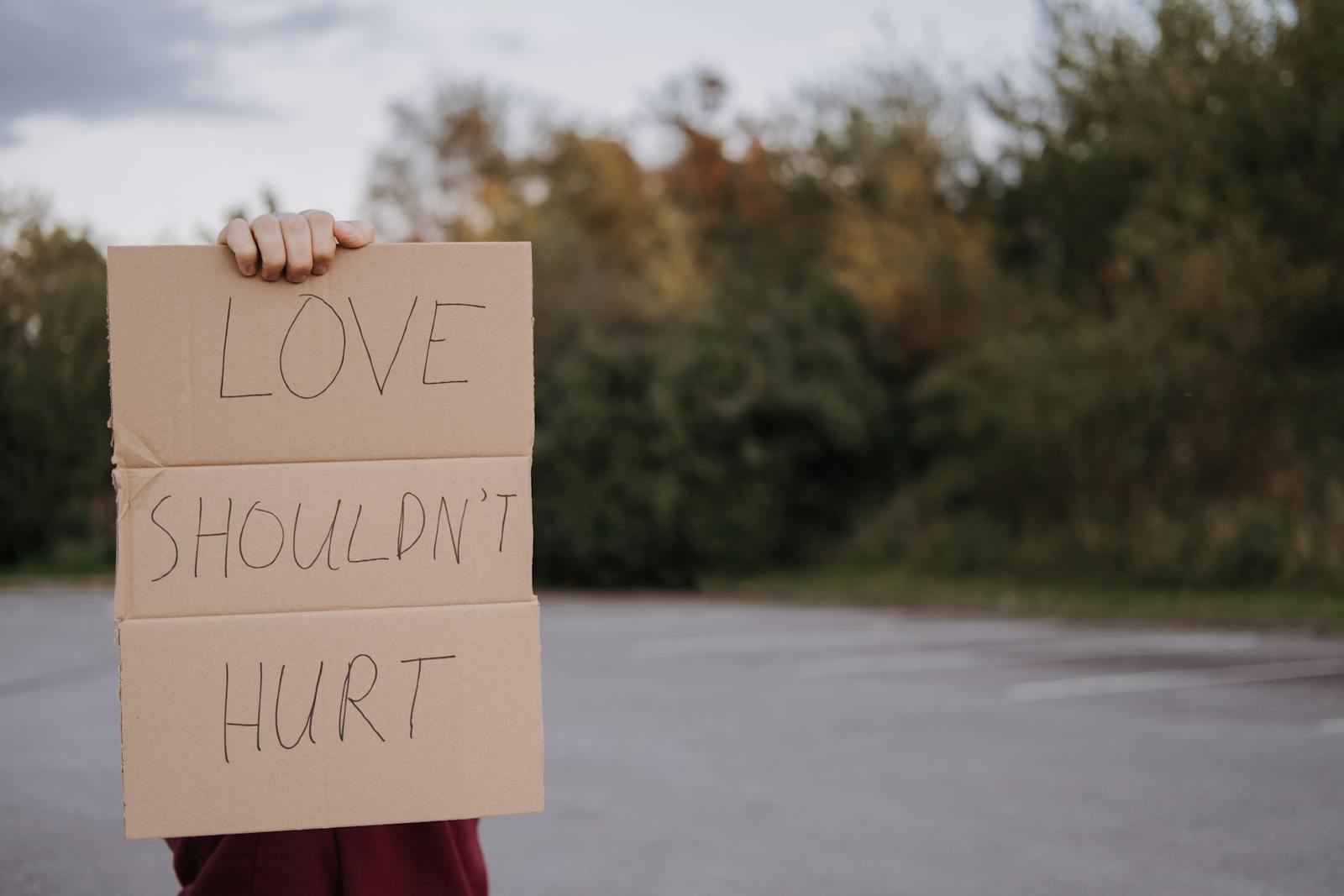 iemand met bindingsangst houdt een bord vast met 'love shouldn't hurt'