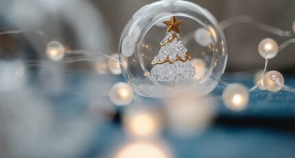 Een glazen kerstboom in een glazen kerstbal temidden van lampjes