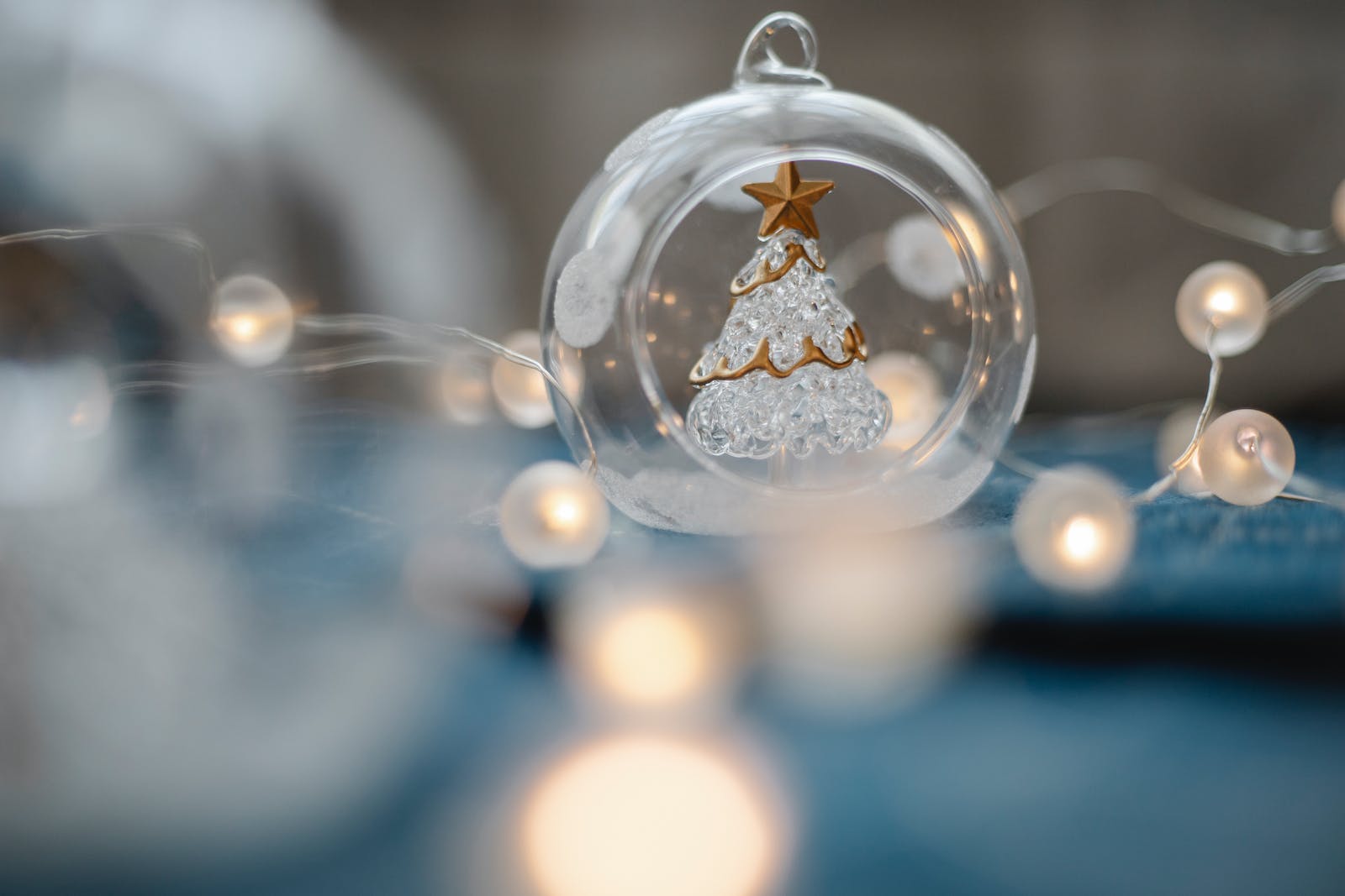 Een glazen kerstboom in een glazen kerstbal temidden van lampjes