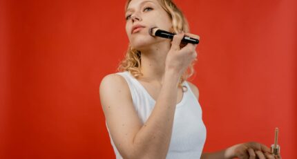 een vrouw in een witte top brengt foundation aan op haar wangen