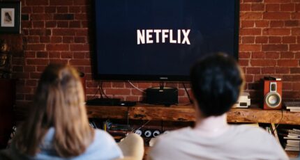 man en vrouw zitten op de bank voor een grote tv met netflix
