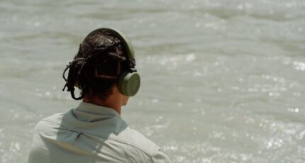 Jongen luistert muziek aan zee via een draadloze koptelefoon