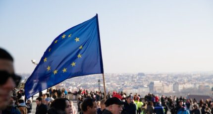Menigte mensen die op straat lopen met wapperende vlag van de Europese Unie tijdens een protest in de stad