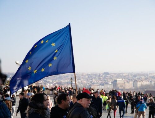 Menigte mensen die op straat lopen met wapperende vlag van de Europese Unie tijdens een protest in de stad