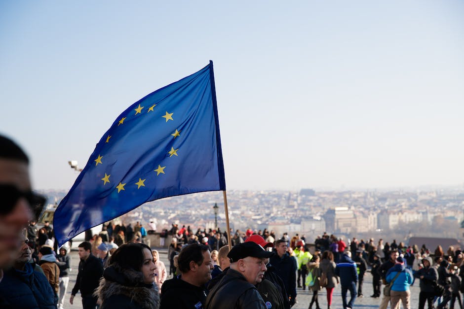 Menigte mensen die op straat lopen met wapperende vlag van de Europese Unie tijdens een protest in de stad