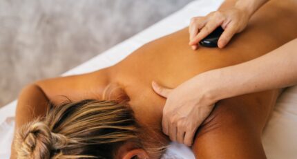 een persoon geeft een mevrouw een hot stone massage