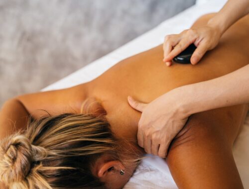 een persoon geeft een mevrouw een hot stone massage