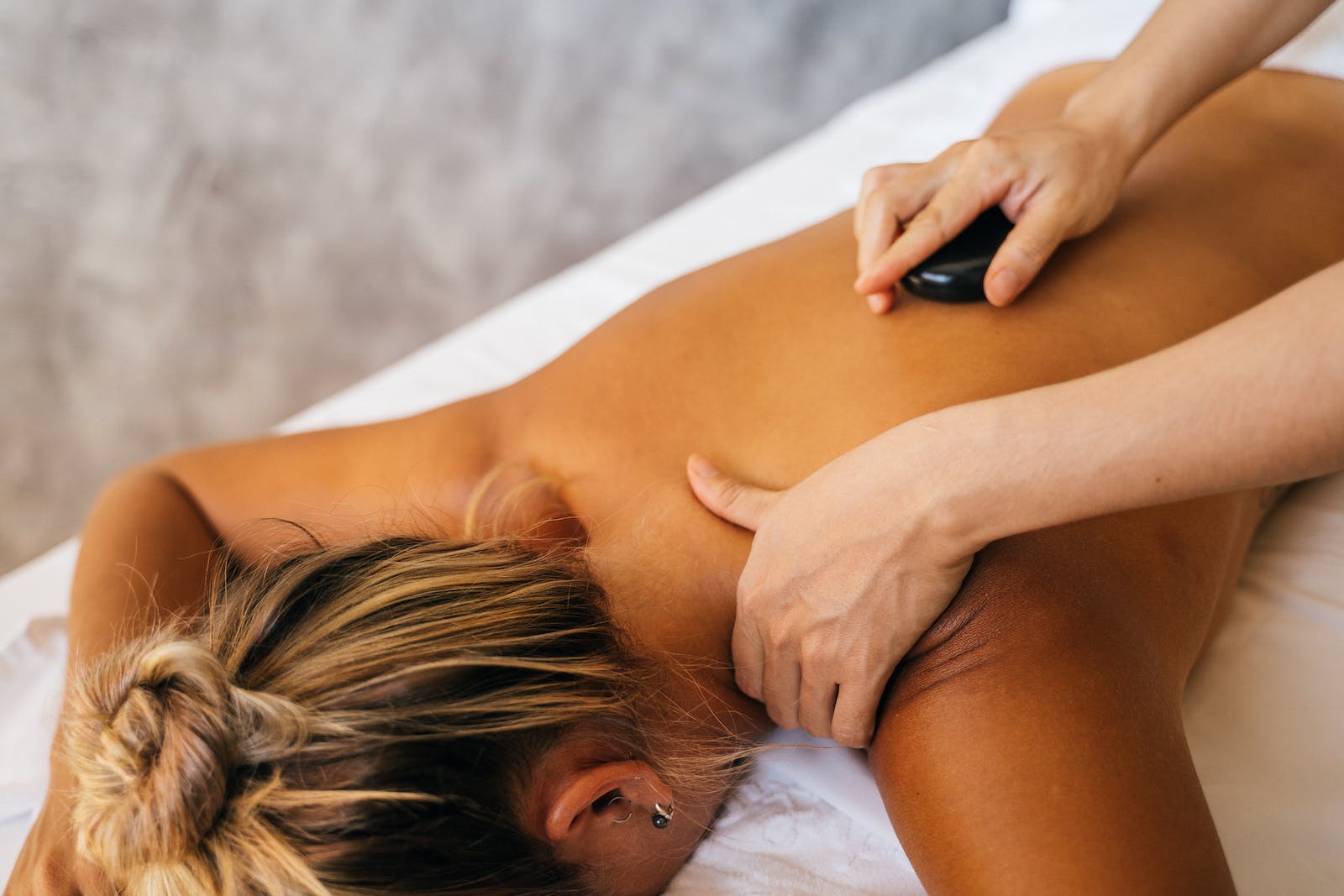 een persoon geeft een mevrouw een hot stone massage