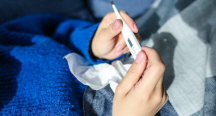 Iemand die op de thermometer controleert of diegene koorts heeft
