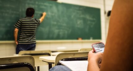 Man in zwart-wit poloshirt naast schrijfbord