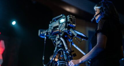 Vrolijke vrouwelijke videograaf die een evenement filmt