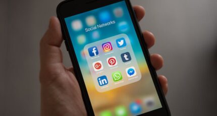 Persoon die een iPhone vasthoudt met de map Sociale netwerken zichtbaar