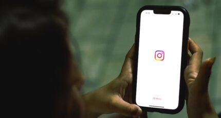 Hand houdt een smartphone vast met het Instagram-icoon op het scherm. iPhone met een logo van een sociale media-app.