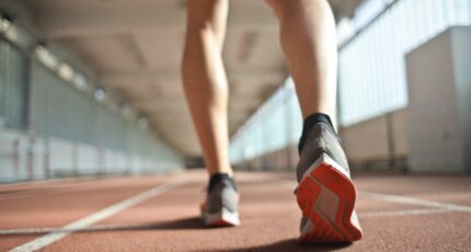 Fit uitziende hardloper staat op een renbaan in een atletiekarena
