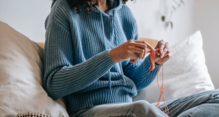 Woman sitting on sofa and doing needlework
