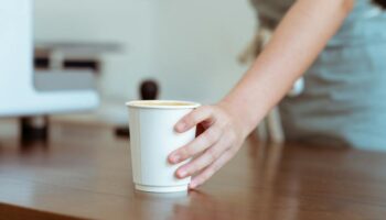 Barista die koffie serveert in papieren beker