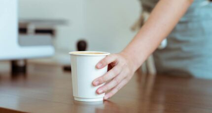 Barista die koffie serveert in papieren beker