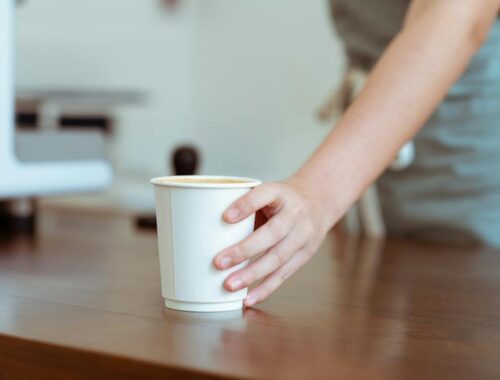 Barista die koffie serveert in papieren beker