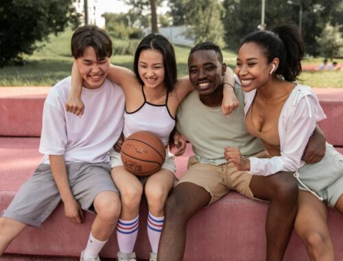 Vrolijke multiculturele vrienden omhelzen op de bank na basketbaltraining