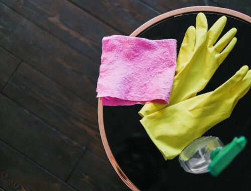Latex handschoenen en fles reinigingsmiddel op tafel in kamer