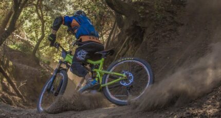 Man in zwart en oranje fietsjack rijdt op groene off-road fiets