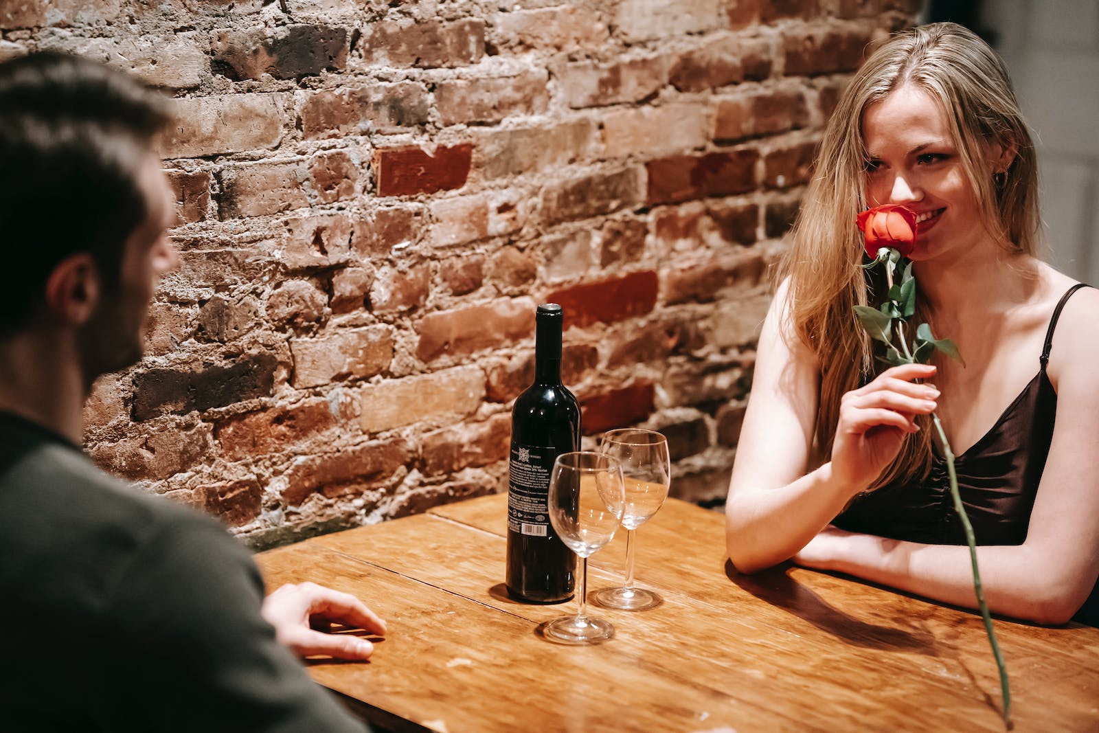 jong koppel zit in restaurant, vrouw houdt rode roos vast en lacht
