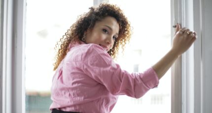 Vrouw die een raam vasthoud of open doet