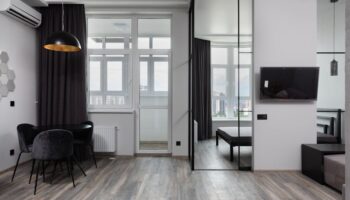 Hedendaagse kamerinterieur met stoelen onder lamp en airconditioning in licht huis met glazen wand