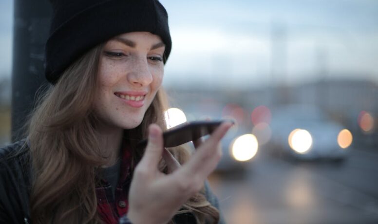 Vrolijke jonge vrouw die 's avonds op straat telefoneert