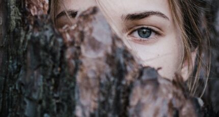 Rustige vrouw achter boomschors in park