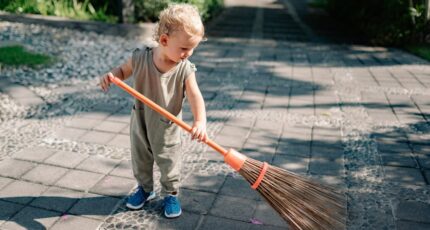 Kind veegt betonstraat met bezem