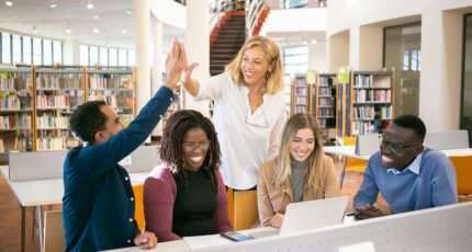 Vrolijke multiculturele studenten die high five geven aan de leraar